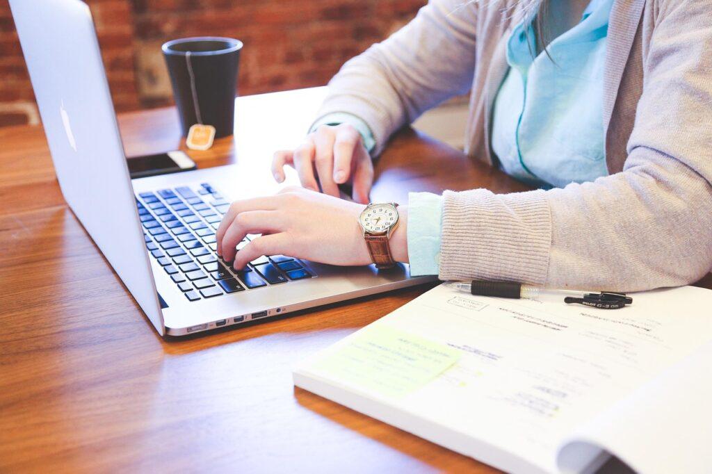 How to Use Hyperbole in Writing, Songwriting, and Poems - Songwriter Typing on a Notebook